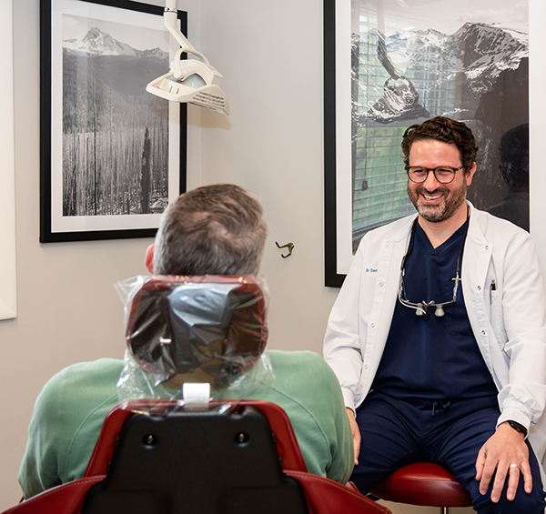 Dr David Perrino smiling at a patient in a dental chair